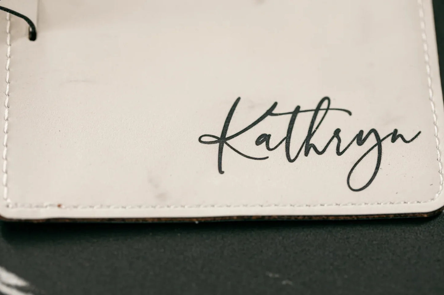 White leather wallet with 'Kathryn' engraved on a dark surface