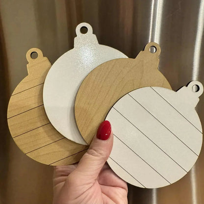 Three wooden coasters with different designs held by a hand against a neutral background