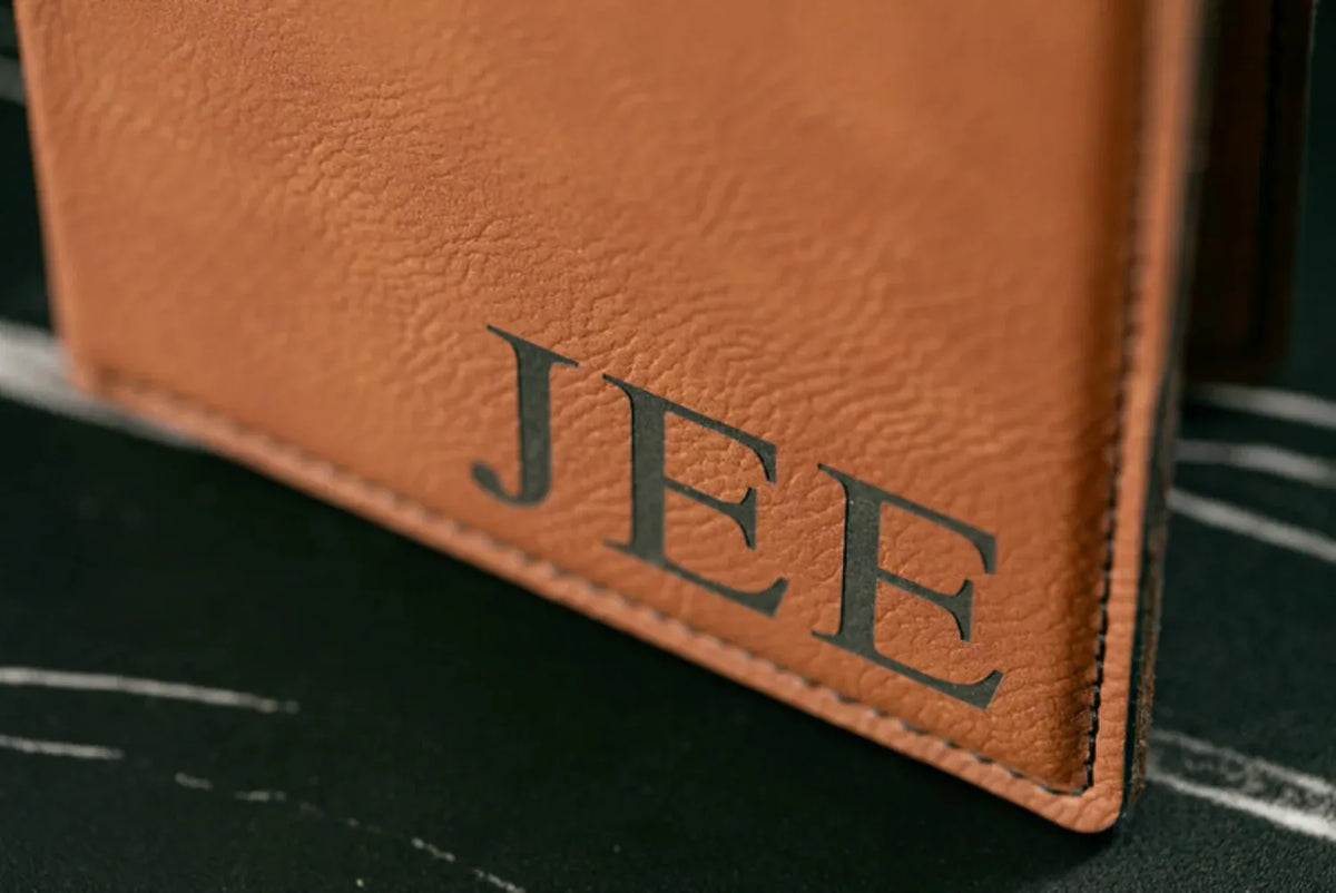 Brown leather wallet with 'JEE' embossed on a dark surface