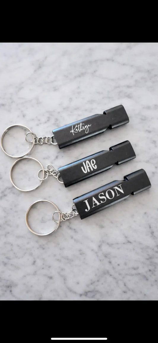 Three black keychains with names engraved on them against a marble background.